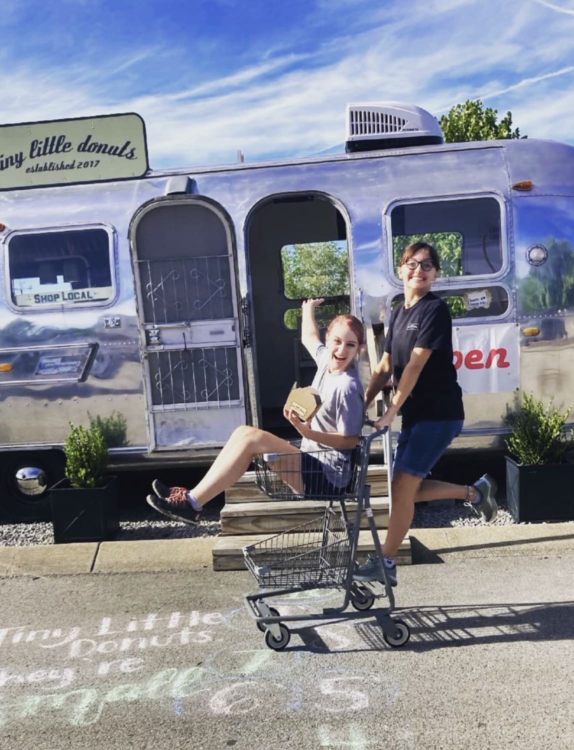 picture of two kids playing in front of the tiny little donuts airstream