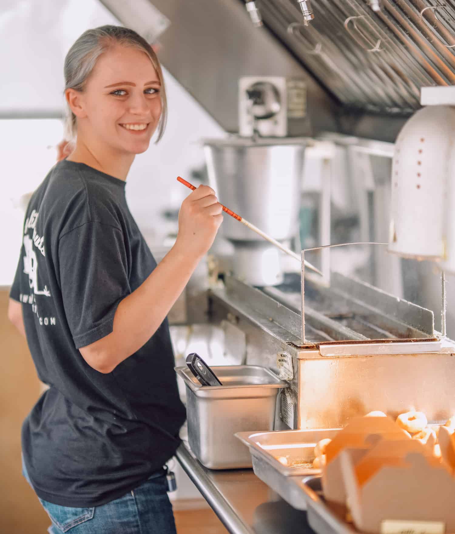 picture of a woman at the tiny little donuts kitchen making donuts